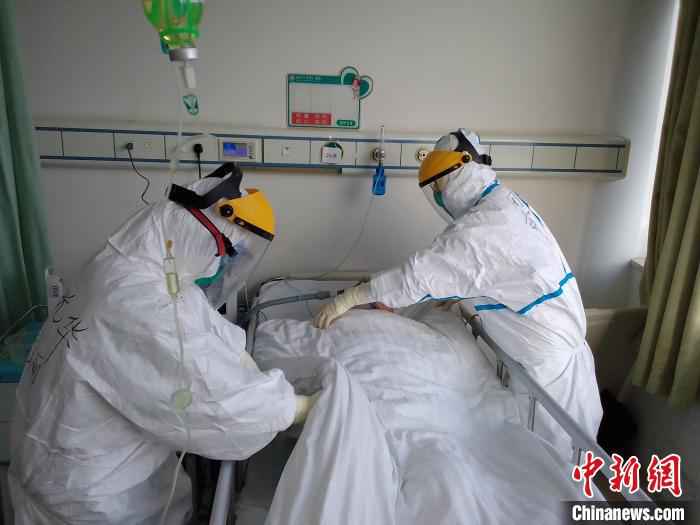 周萍(右)在护理病人。受访者供图 上海援助湖北护士周萍:“病人欢欢喜喜出院是对我们的最大安慰”